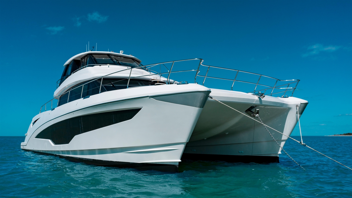 Luxury white catamaran yacht anchored in clear blue water against a bright sky, showcasing modern design and sleek lines.